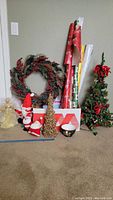 Photo showing the small pre-lit Christmas tree decorated with red berries, green pine wreath with red berries, snowmen figurines, gift wrapping papers and bags, and a small gold decorative cone tree.