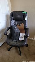 Black pleather office chair with filing tote and clipboard placed on it, showing overall condition and items included.