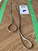 Two silver chains laid flat on a wood surface showing the length and chain texture.
