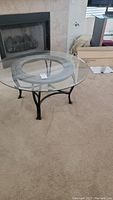 Full view of round glass top coffee table with black metal base and glass removable top.