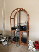 Front view of a tall wood media center with glass shelves, electronics visible but not included.