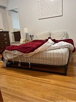 Side perspective of aluminum bed frame and mattress in bedroom setting.