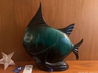Front angle view of fish sculpture showing detailed face and base with blue-green glaze