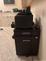 Side view showing the black wood file cabinet with three drawers and the HP printer on top.