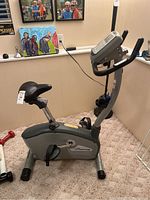 Side view showing durable gray Nautilus exercise bike with black cushioned saddle, digital display console, and pedal straps.