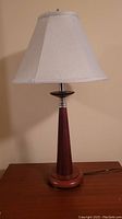 Photo of one of the two matching table lamps with wooden base and beige fabric shade taken from front view.