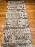 Full view of the grey and white patterned rug showing its abstract textured design on a hardwood floor.