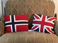 Photo showing two cushions on a patterned sofa, left cushion with Norway flag, right cushion with Union Jack flag