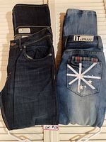 Two pairs of jeans folded side by side showing front and back pocket details