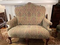 Front view of vintage upholstered loveseat showing patterned upholstery and wooden cabriole legs.