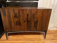 Front view showing two doors, wood veneer finish, round knobs, metal legs