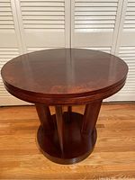 Front perspective side view showing round top, four angled legs connecting top to circular base, rich dark brown color, glossy finish.