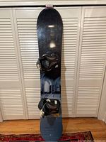 Front view of the K2 snowboard showing graphic top sheet with architectural image and mounted Flow FL-4 bindings.