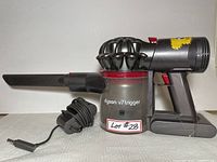 Side view of Dyson V7 Trigger handheld vacuum with crevice tool and charging adapter cable.