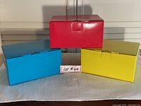 Three closed boxes in different colors matching the appliances inside: red, yellow, and blue.