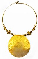 Full view of the brass necklace showing the large round etched pendant and brass beads on a brass wire.