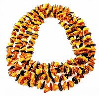 Photo of the full necklace showing the amber chip beads in multiple color tones arranged in a loop.