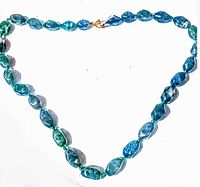 Full view of vintage polychromatic blue and green apatite bead necklace arranged in a heart shape with a metal clasp visible.