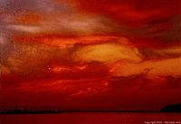 Close-up view of the watercolour painting, showing the vibrant red and orange sky with clouds and the silhouetted horizon.