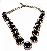 Front angled view showing the necklace's black faceted beads and gold-tone chain with clasp.