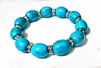 Photo showing the full circular turquoise-colored stretch bracelet with rhinestone spacers against white background.