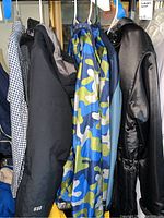 Five boys outerwear items on hangers including multiple jackets and raincoats in different colors