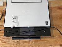 Canon Pixma TS9020 printer with visible top white panel, black front control panel with touchscreen, power cord running across device.