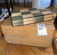 Wooden closed case showing chess board pattern on top, placed on a wooden box with MaxSold tag