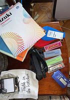 Overview photo of the lot showing music books, harmonicas, carrying cases, metronome, and strap.