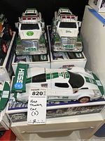 Three Hess vehicles: two trucks and one race car all on or near their original boxes with visible Hess logos and packaging details.