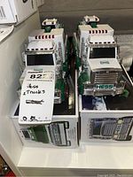 Two white and green Hess collectible trucks in original packaging