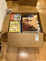 Top down view of the open box containing Japanese books, including a manga set and a large hardcover book with a nature photo cover.