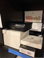 Shelf with stacked boxes including Guy Laroche jewelry box and Novir wallets