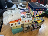 Stack of multiple kids shoe boxes from brands Stride Rite, Deer Stags, and Clarks plus two packages of Hickies elastic shoelaces, all placed on a table.