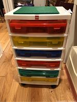 Front view of white LEGO storage tower with six colored drawers and green baseplate