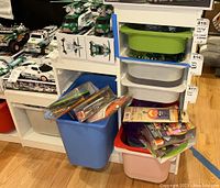 Side view of white IKEA TROFAST storage unit with seven plastic tubs in different colors, showing the tubs and the items around it