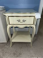 Front view of the nightstand showing drawer and gold trim