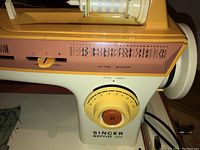 Close-up of the Singer sewing machine model 2404 showing stitch pattern options, stitch length dial, and start/stop button.