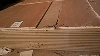 Stack of full drywall sheets, side view showing thickness and paper layers