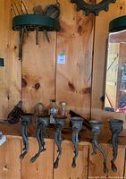 Front view of six cast iron meat and vegetable grinders clamped on a wooden shelf, showing varied sizes and design of the grinders.