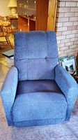 Front view of blue upholstered recliner chair showing padded seat, armrests, and backrest
