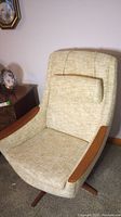 Angled side view showing upholstery, teak armrest and base.