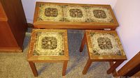 Wide shot of all three tables showing tile centers and wooden frames with wear and water stains.