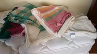 Two vintage wool blankets and throws staged on a mattress showing different textures and colors.