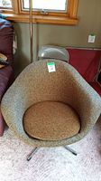 Front view of tub chair showing rounded tweed fabric back and removable seat cushion, with metal swivel base visible beneath.