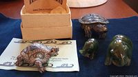 Photo showing all four figurines: two jade bears, clay turtle in box with card, and resin turtle missing tail
