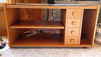 Full frontal view of wooden TV stand showing the pull-out shelf and four storage drawers on right side.