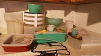 Wide view showing various vintage Tupperware containers and accessories including meat marinating container, cake and pie carriers, juice pitcher, vegetable containers, and small kitchen accessories.