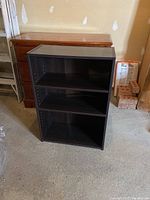 Front view of a small dark brown bookshelf showing three shelves and smooth finish.