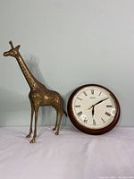Brass giraffe statue next to Seiko wooden clock, showing relative size and condition.